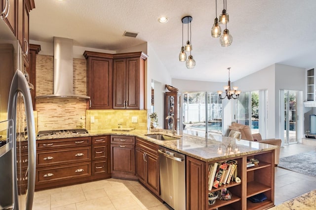 kitchen featuring sink, decorative light fixtures, kitchen peninsula, stainless steel appliances, and wall chimney range hood