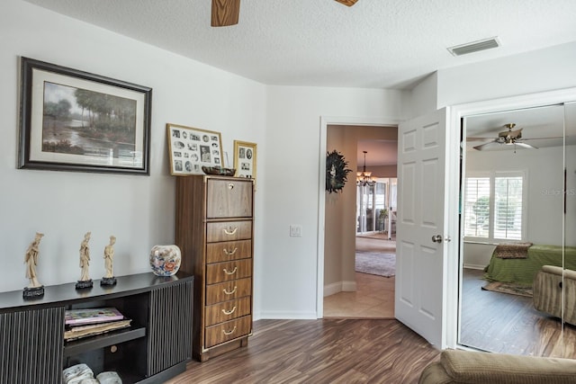 interior space featuring dark wood-type flooring, ceiling fan with notable chandelier, and a textured ceiling