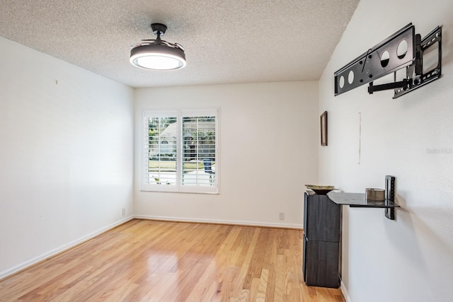 unfurnished room featuring wood-type flooring and a textured ceiling