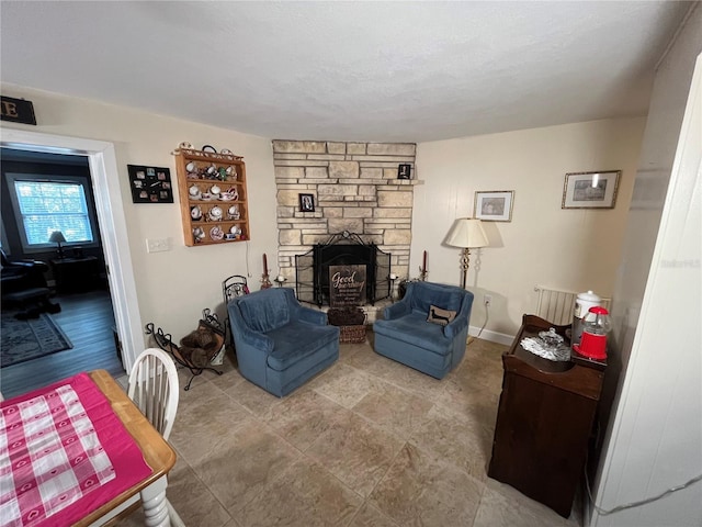 living room with baseboards, a stone fireplace, and a textured ceiling