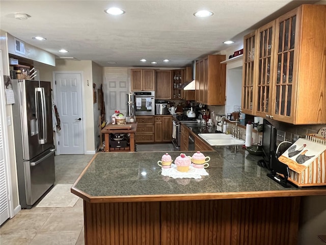 kitchen featuring stainless steel appliances, dark countertops, glass insert cabinets, and a sink