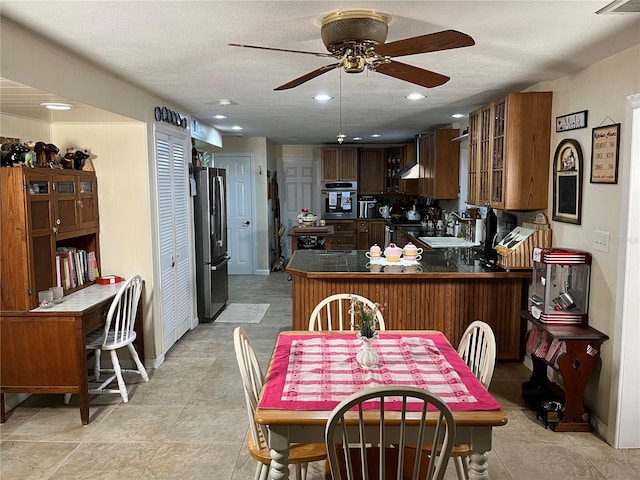 kitchen with stainless steel appliances, a peninsula, a sink, dark countertops, and glass insert cabinets