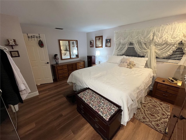 bedroom with dark wood-style floors, visible vents, and baseboards