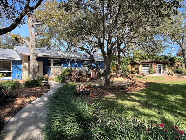 ranch-style home featuring a front yard and metal roof