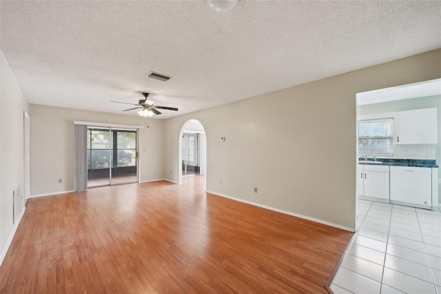 empty room featuring ceiling fan, sink, light hardwood / wood-style flooring, and a textured ceiling