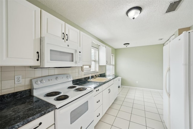 kitchen with sink, backsplash, white cabinets, light tile patterned floors, and white appliances