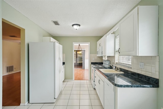 kitchen featuring light tile patterned flooring, white cabinetry, backsplash, white appliances, and a textured ceiling