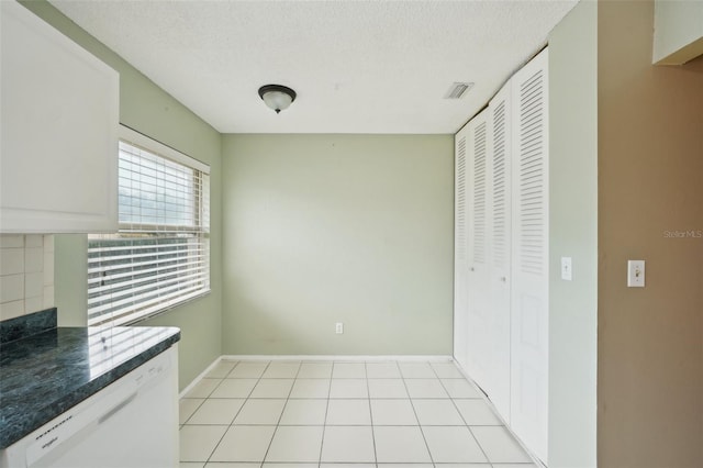 interior space featuring light tile patterned flooring, a textured ceiling, white cabinets, and white dishwasher