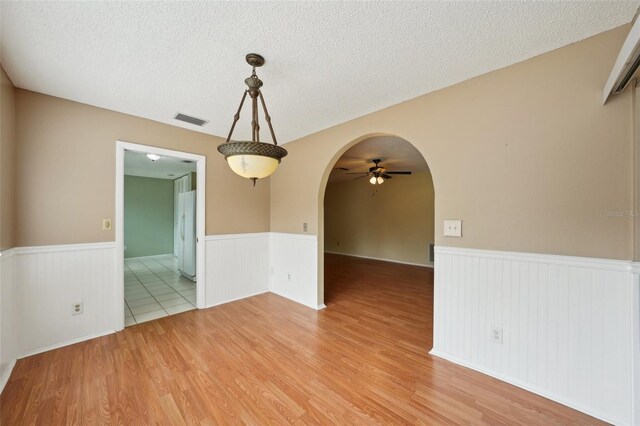 unfurnished room featuring ceiling fan, light wood-type flooring, and a textured ceiling