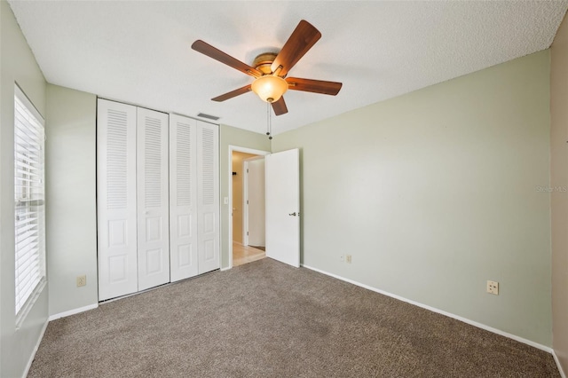 unfurnished bedroom featuring multiple windows, carpet floors, ceiling fan, and a closet