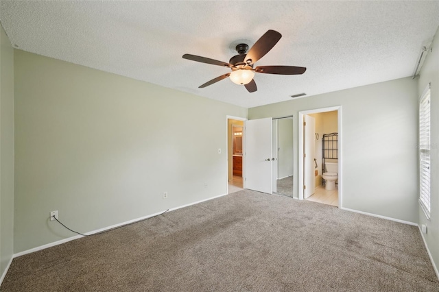 unfurnished bedroom featuring ceiling fan, light colored carpet, ensuite bathroom, and a textured ceiling