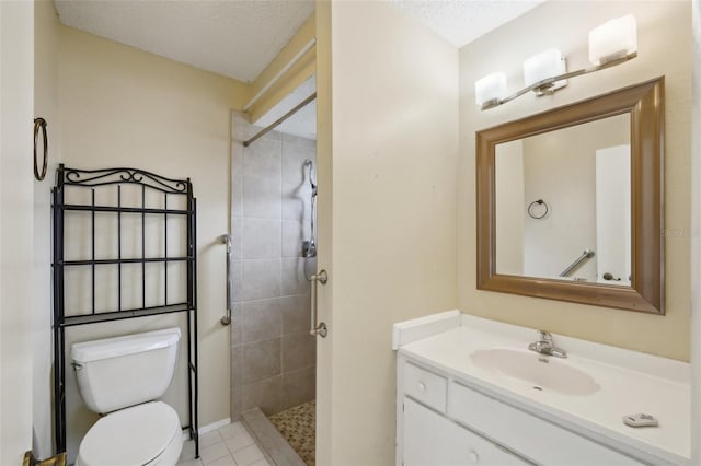 bathroom with tiled shower, vanity, toilet, and a textured ceiling