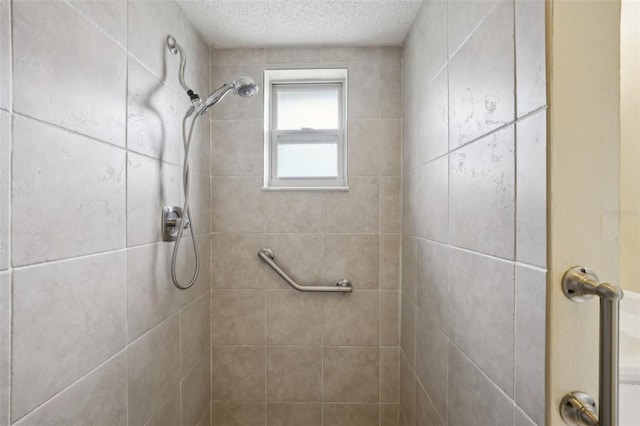 bathroom with a textured ceiling and tiled shower