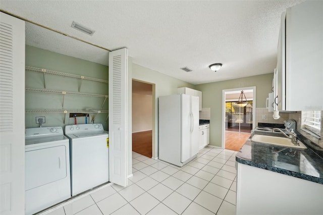 kitchen featuring washer and dryer, white cabinetry, sink, light tile patterned floors, and white appliances