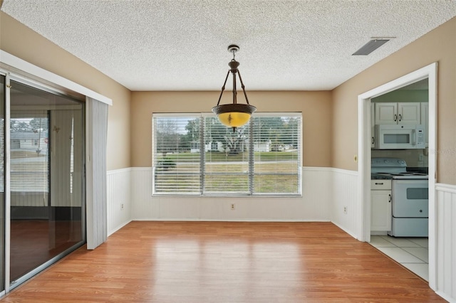 unfurnished dining area featuring light hardwood / wood-style floors and a textured ceiling