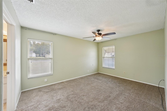 carpeted spare room with ceiling fan and a textured ceiling