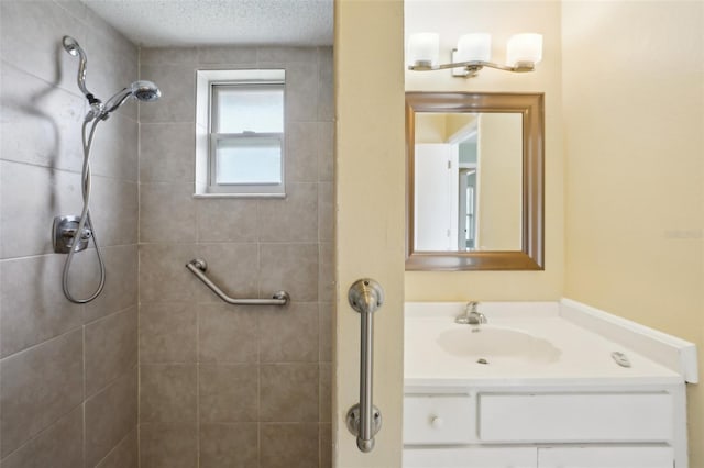 bathroom with vanity, tiled shower, and a textured ceiling