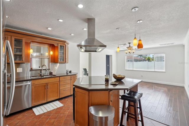 kitchen featuring sink, hanging light fixtures, island exhaust hood, a center island, and stainless steel appliances