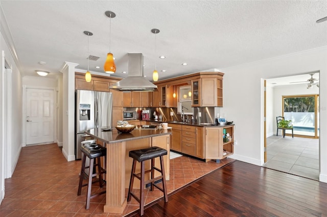 kitchen with pendant lighting, crown molding, hardwood / wood-style flooring, appliances with stainless steel finishes, and island range hood