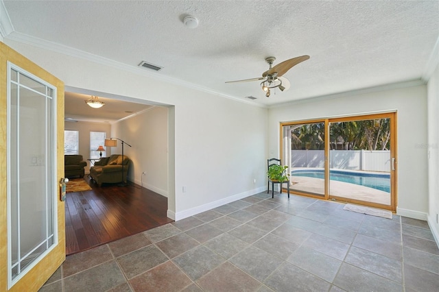 unfurnished room with ceiling fan, ornamental molding, and a textured ceiling