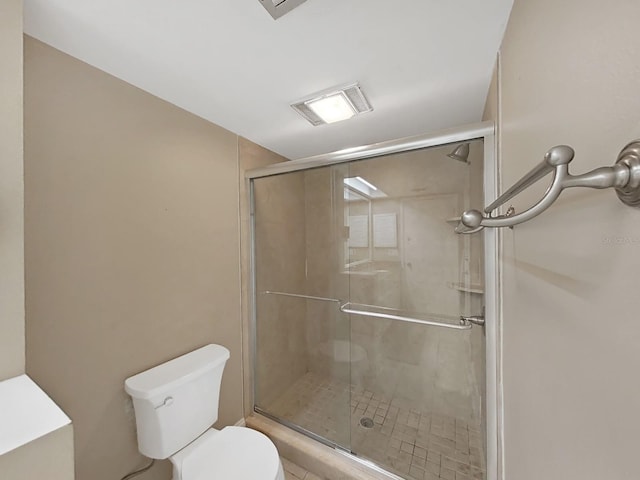 bathroom featuring toilet and a shower with shower door