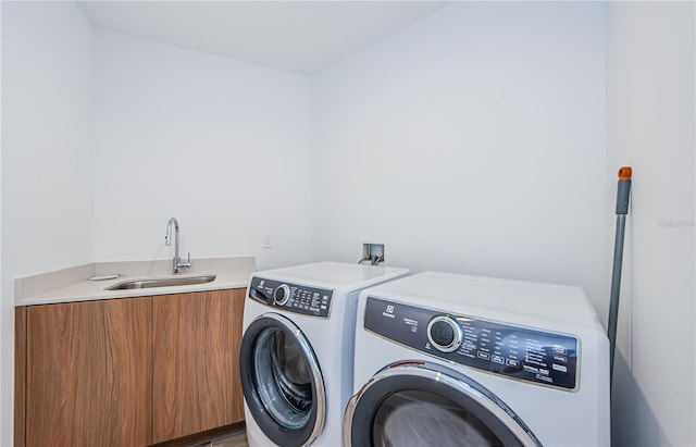 clothes washing area featuring cabinets, washer and clothes dryer, and sink