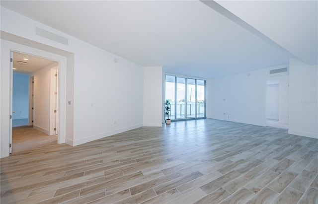 empty room with a wall of windows and light wood-type flooring