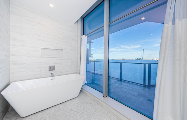 bathroom featuring tile patterned flooring, a bathtub, and tile walls