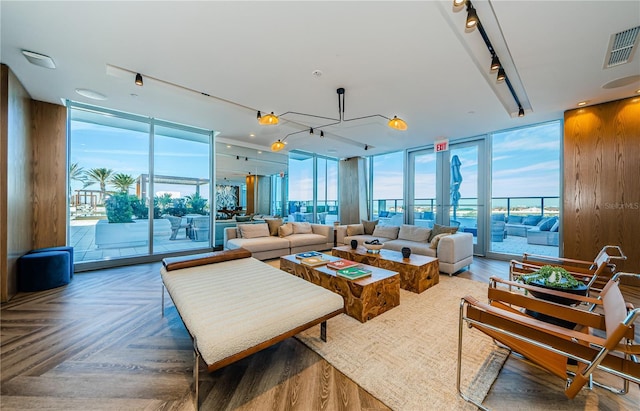 living room with parquet floors, a wealth of natural light, a wall of windows, and rail lighting