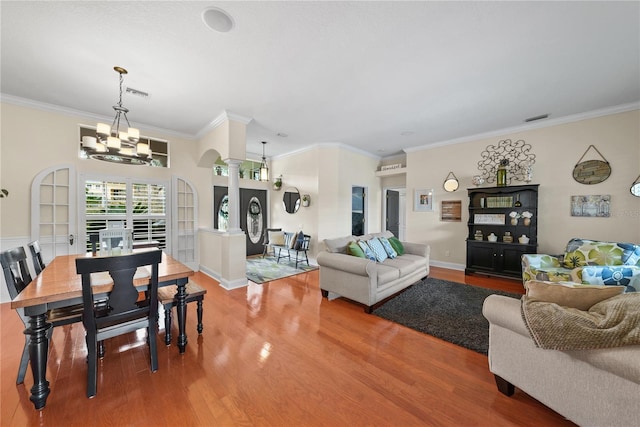 living room with hardwood / wood-style flooring, ornamental molding, a chandelier, and ornate columns