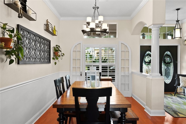 dining room featuring crown molding, wood-type flooring, decorative columns, and a chandelier