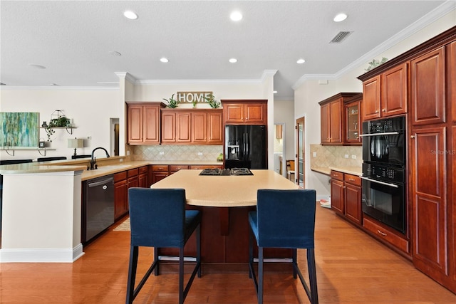 kitchen with sink, light wood-type flooring, a kitchen breakfast bar, kitchen peninsula, and black appliances