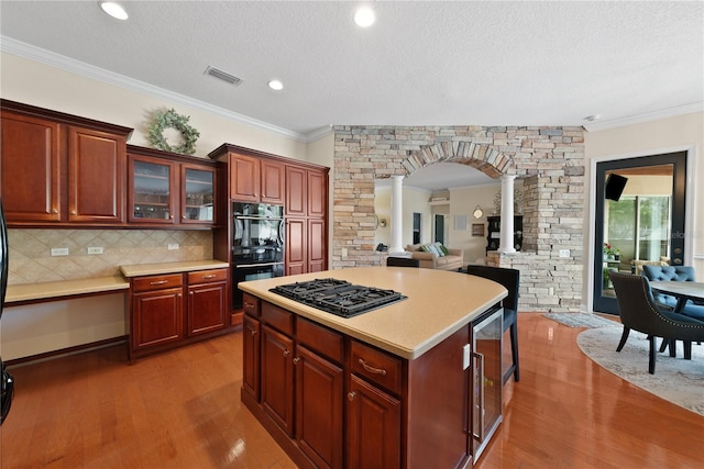 kitchen with crown molding, a center island, hardwood / wood-style floors, and black appliances