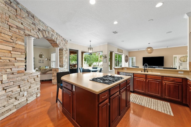 kitchen with sink, appliances with stainless steel finishes, a center island, decorative light fixtures, and ornate columns