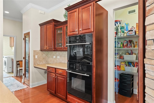 kitchen featuring hardwood / wood-style flooring, black double oven, ornamental molding, and backsplash