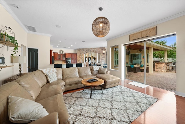 living room featuring hardwood / wood-style floors, crown molding, and a textured ceiling