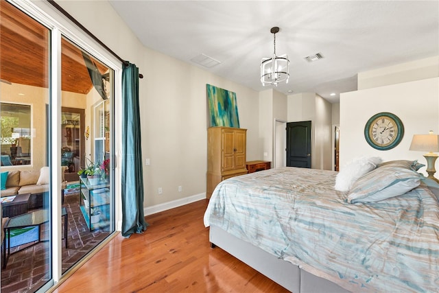 bedroom with hardwood / wood-style flooring, access to exterior, and an inviting chandelier