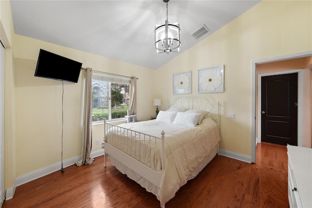 bedroom featuring lofted ceiling, hardwood / wood-style floors, and an inviting chandelier