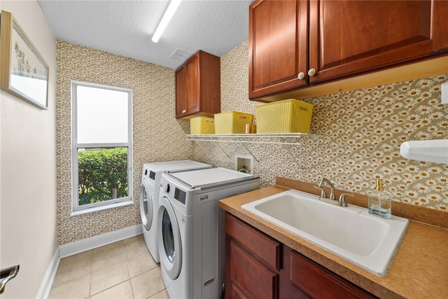 laundry area with sink, cabinets, light tile patterned floors, washing machine and clothes dryer, and a textured ceiling