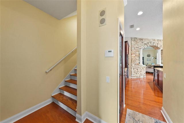 staircase with hardwood / wood-style floors and a textured ceiling