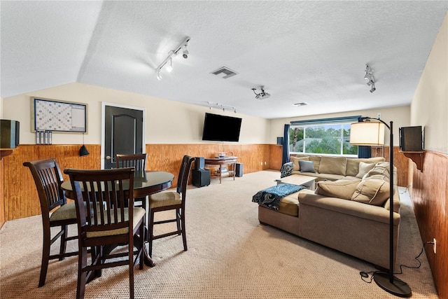 carpeted living room featuring vaulted ceiling, a textured ceiling, and wood walls