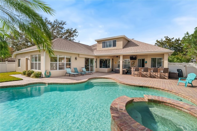 rear view of house featuring a swimming pool with hot tub, a patio area, and ceiling fan