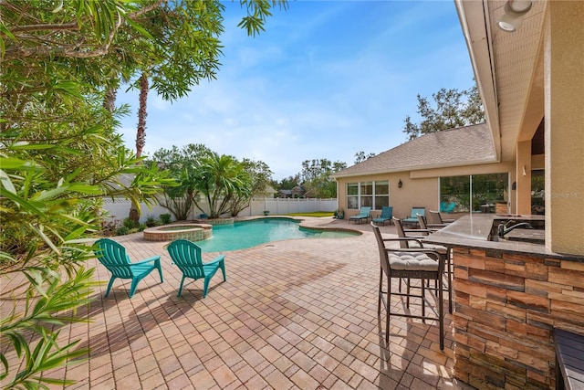 view of pool with an in ground hot tub, a patio, and an outdoor wet bar