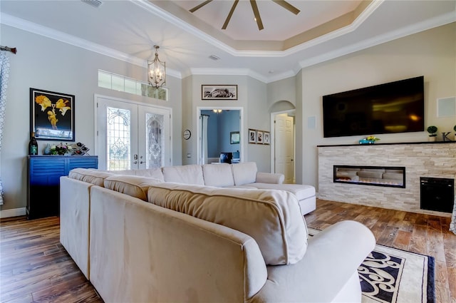 living room featuring a fireplace, wood finished floors, french doors, a tray ceiling, and crown molding