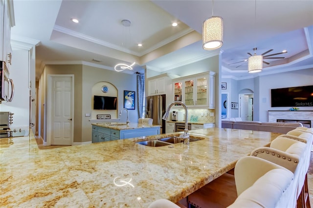 kitchen with light stone countertops, arched walkways, a raised ceiling, and a sink