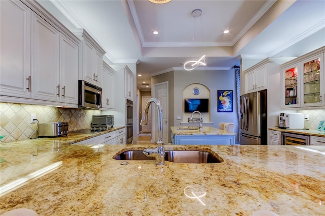 kitchen featuring stainless steel appliances, a sink, light stone countertops, a raised ceiling, and glass insert cabinets