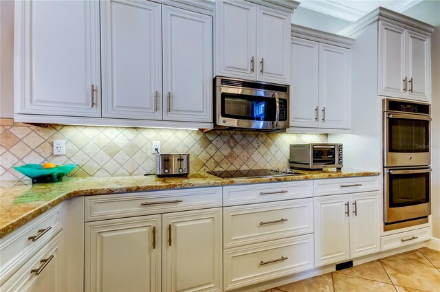 kitchen featuring light tile patterned floors, a toaster, decorative backsplash, light stone countertops, and stainless steel appliances