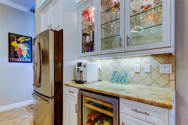 kitchen featuring wine cooler, freestanding refrigerator, light stone countertops, glass insert cabinets, and crown molding