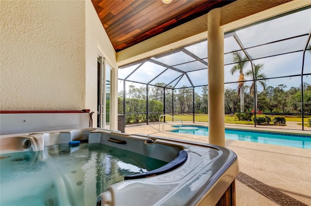 outdoor pool featuring a patio area, a hot tub, and glass enclosure