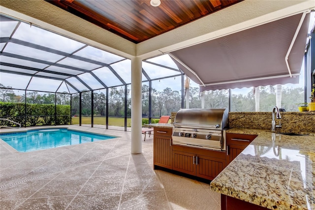 pool featuring an outdoor kitchen, a patio, grilling area, a lanai, and a sink